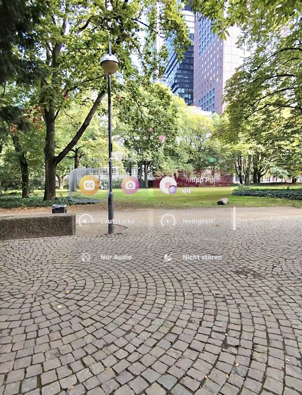 Bedienoberfläche der Meta Ray-Ban Display vor Park und Pflaster in Frankfurt, mit Lautstärke und Nicht stören