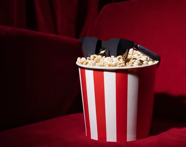 RayNeo GT als Kino-Brille — schwarzes Visier auf einem Popcornbecher im Kinosaal